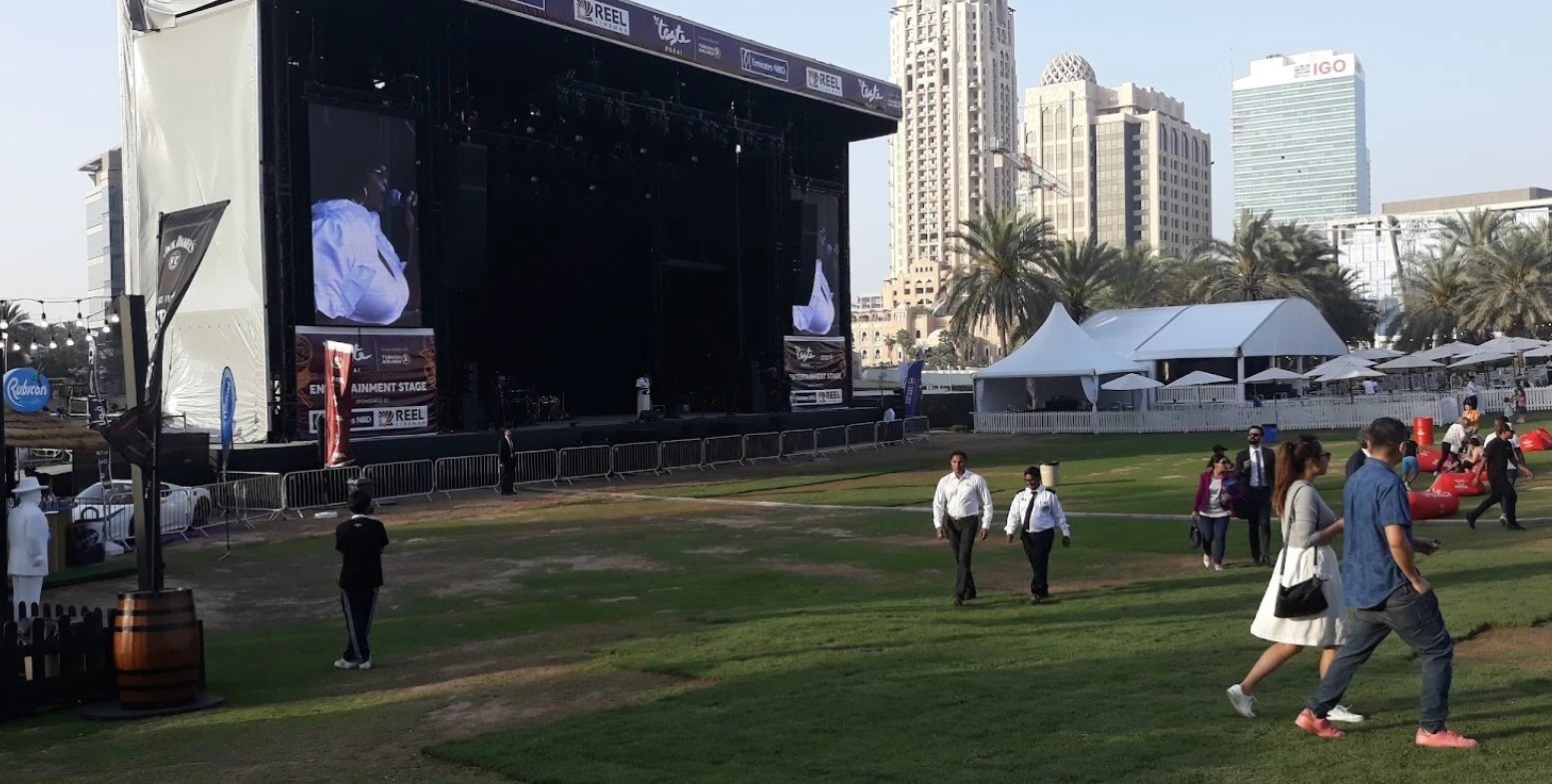 Dubai Media City Amphitheatre stage with people walking, Dubai skyline visible.