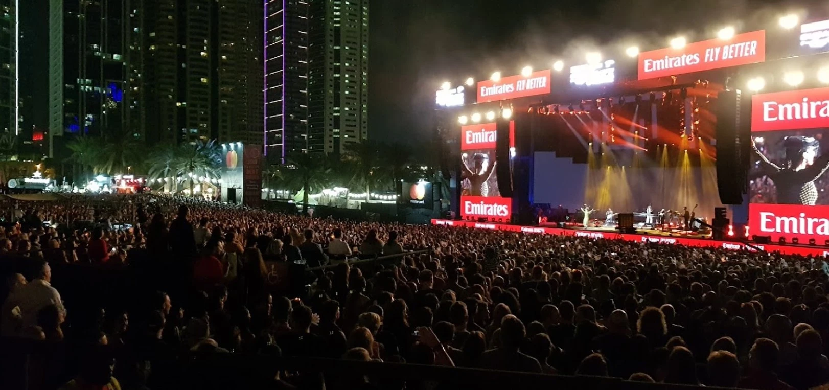 Crowd enjoying concert at Dubai Media City Amphitheatre, night view.