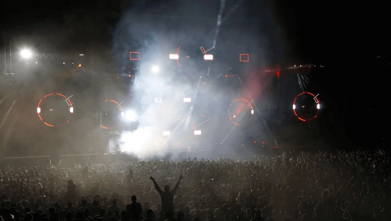 Crowd enjoying concert at Dubai Media City Amphitheatre, vibrant lights.