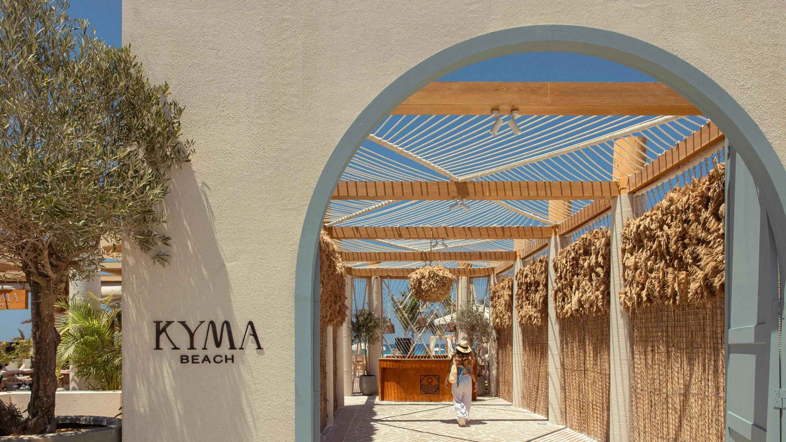 Entrance to Kyma Beach Dubai with wooden pergola and greenery.
