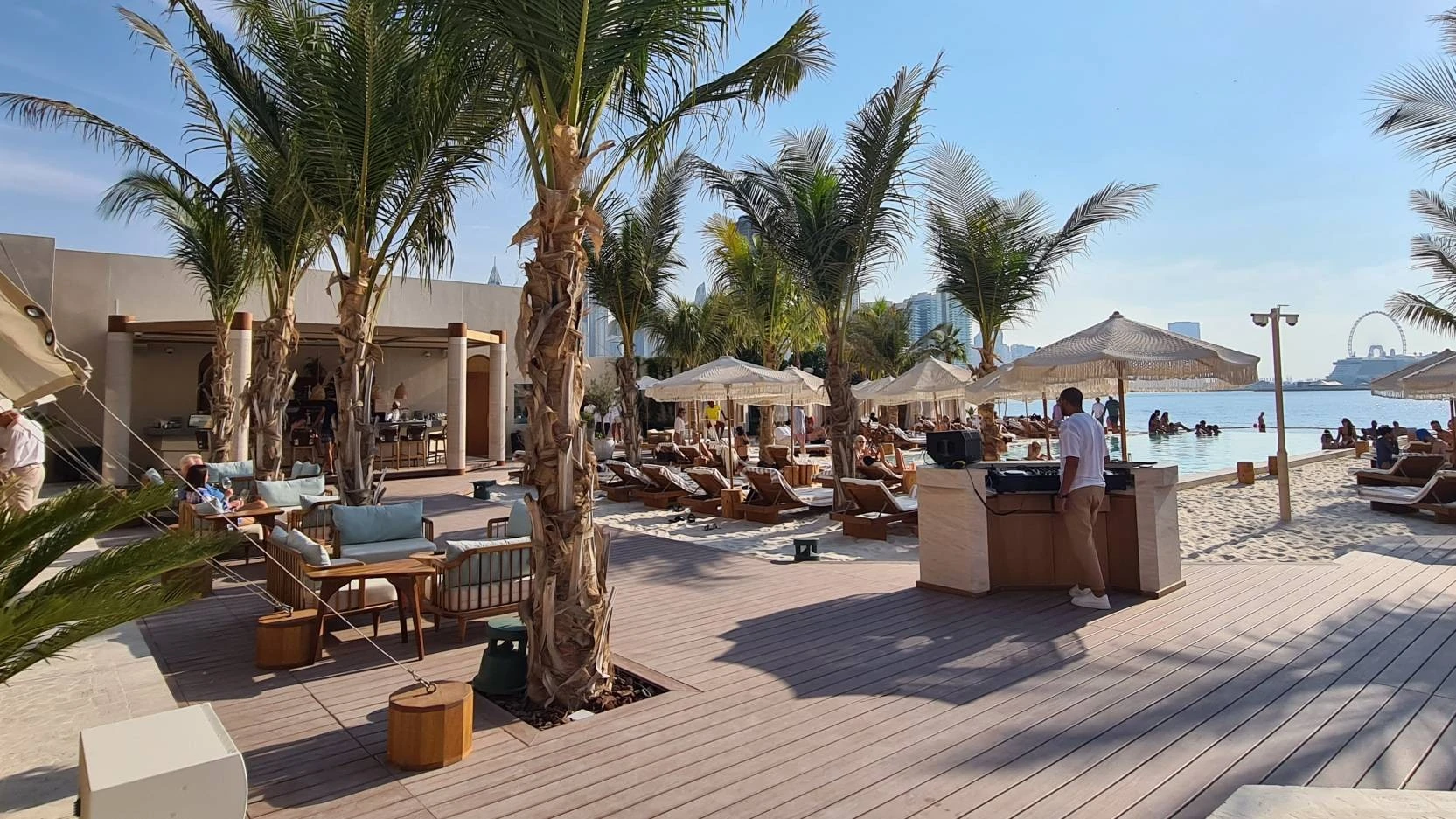 Kyma Beach Dubai with palm trees and lounge chairs by the sea.