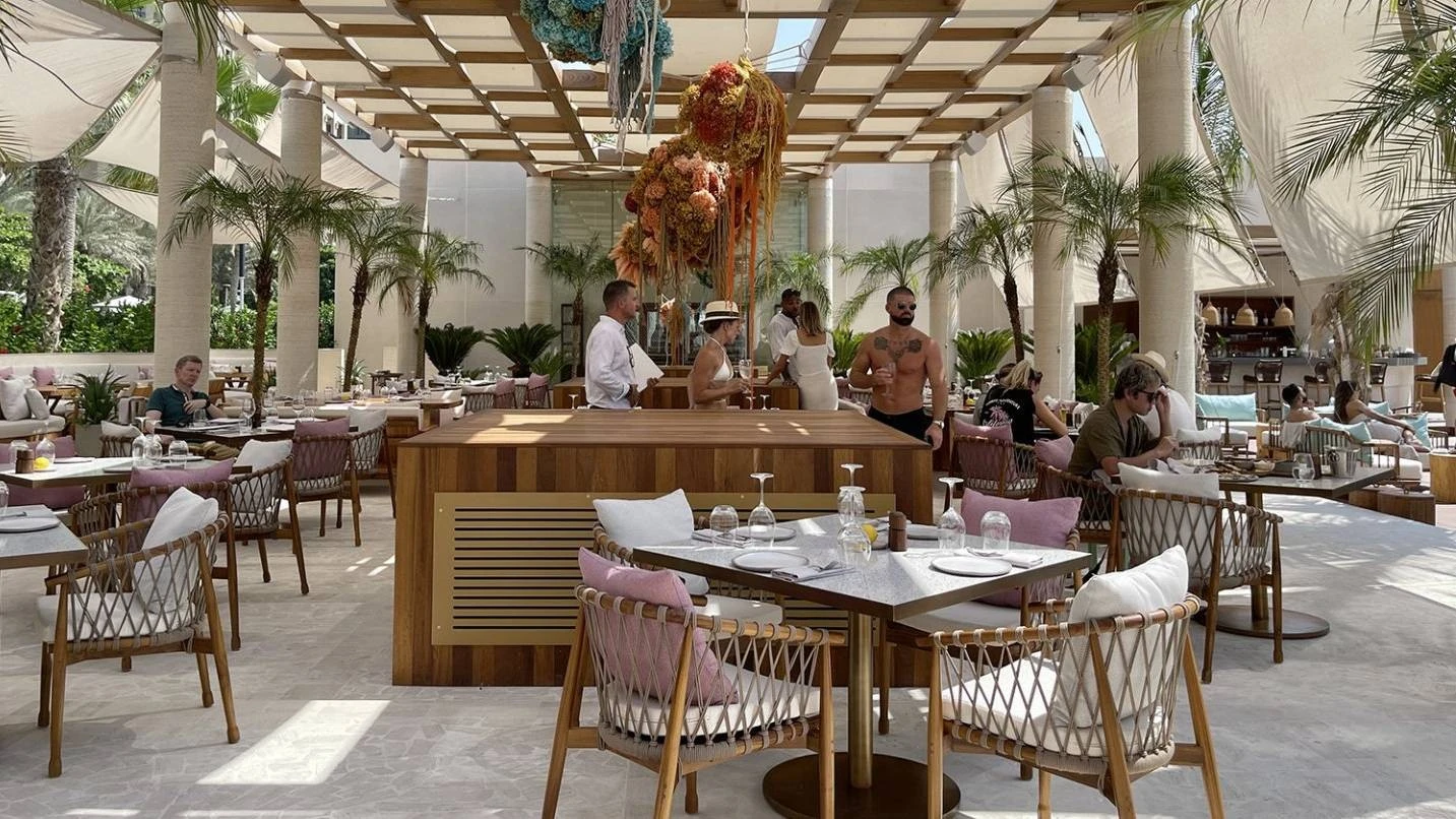 Outdoor dining area at Kyma Beach Dubai with palm trees.