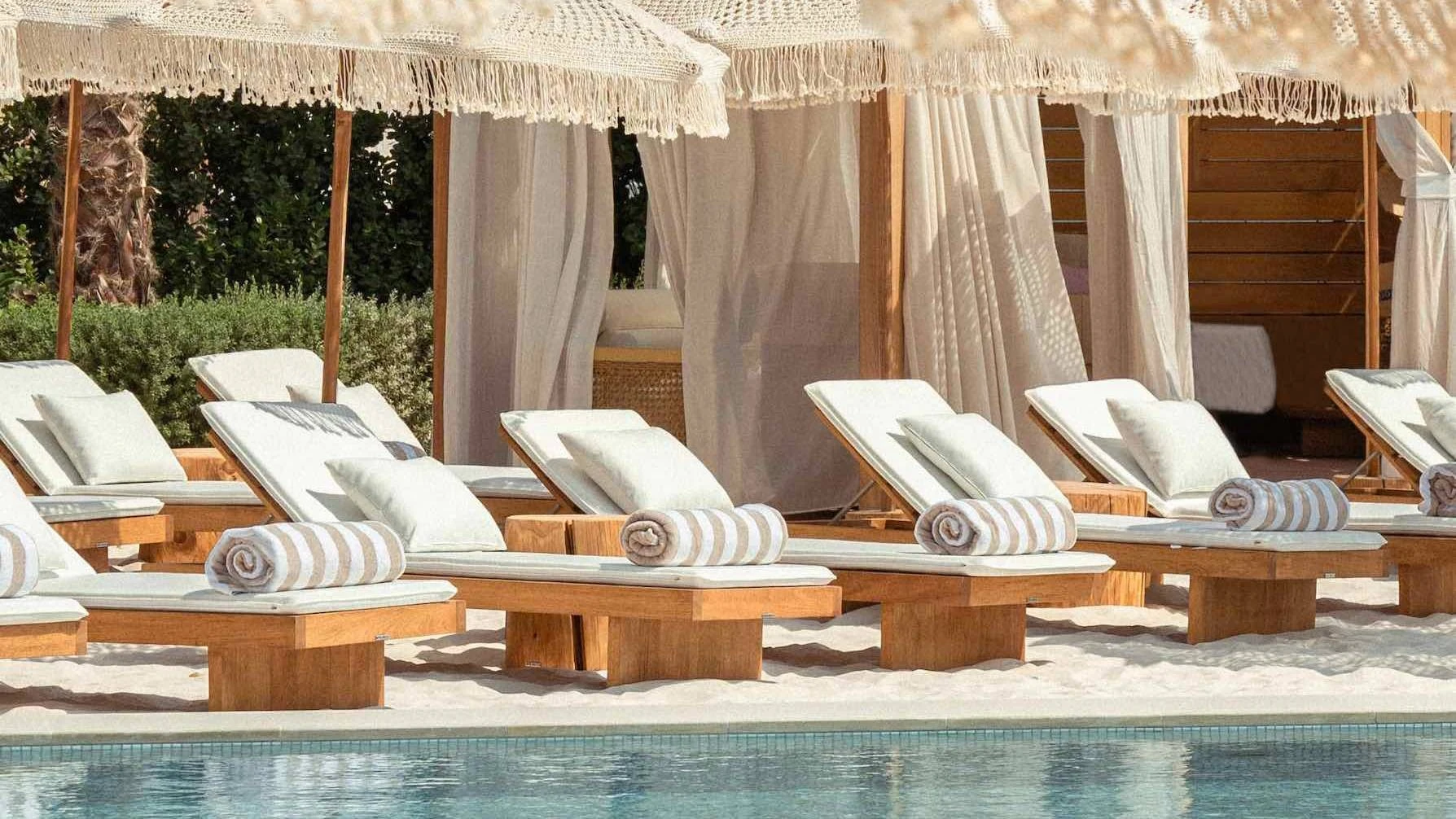 Kyma Beach Dubai sun loungers by poolside with cabanas.