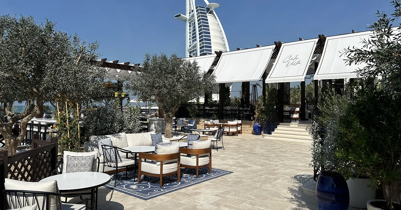 Cala Vista Dubai outdoor seating with Burj Al Arab view.