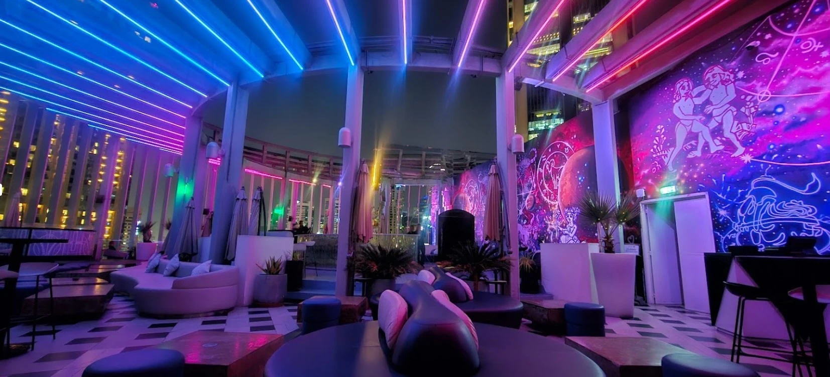 Vibrant rooftop lounge at Atelier M, Dubai with colorful neon lights.