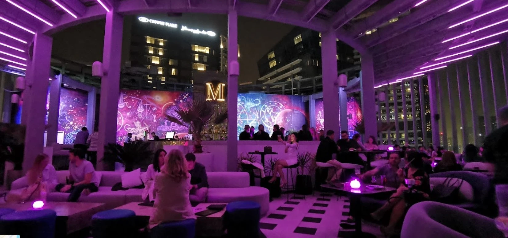 Atelier M rooftop lounge with purple lighting, Dubai skyline view.