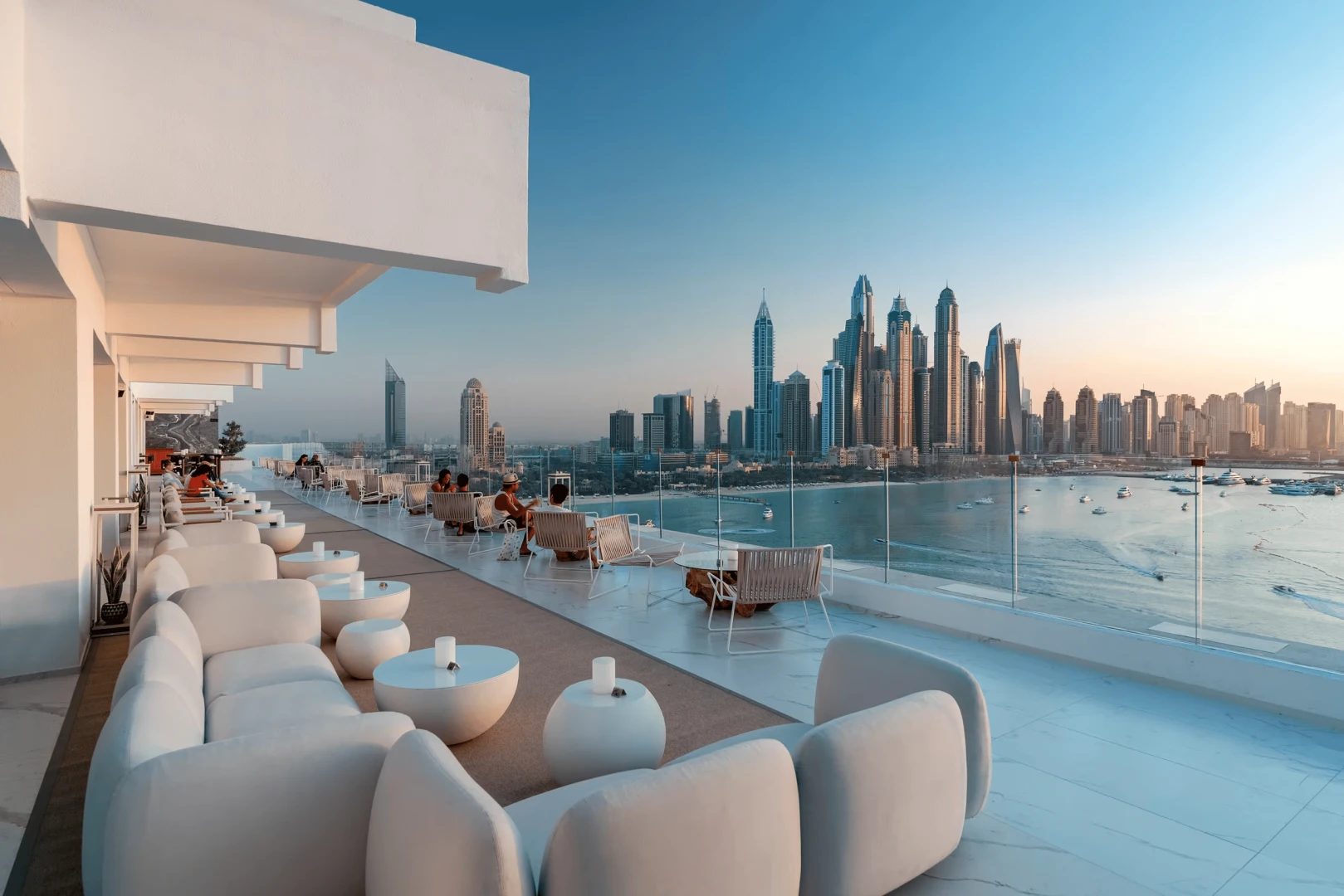 Elegant rooftop seating with panoramic Dubai skyline at sunset.