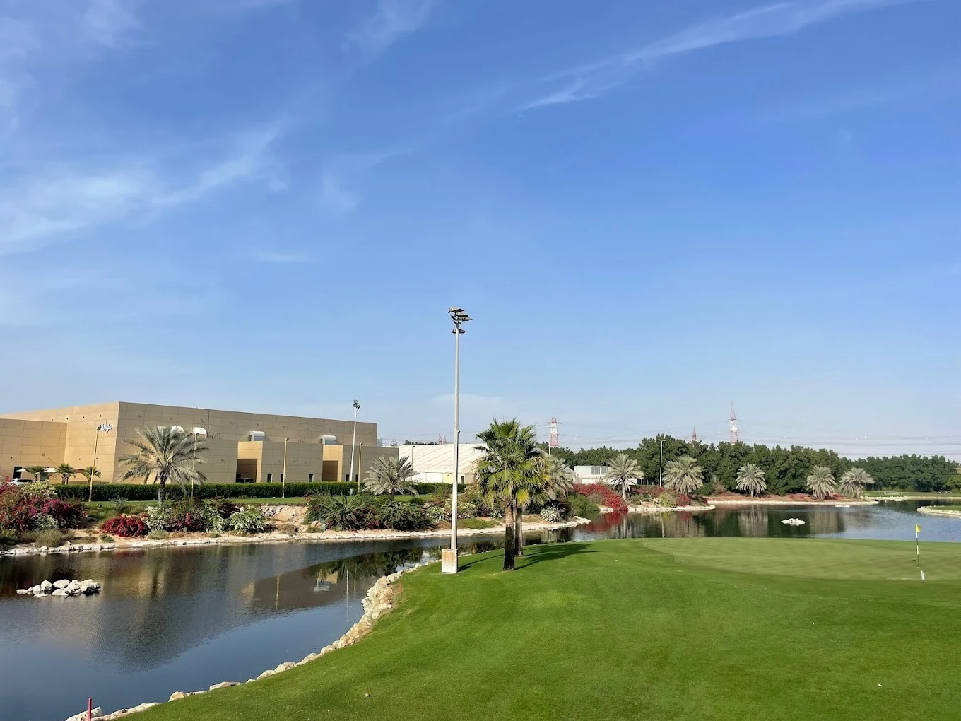Sharjah Golf and Shooting Club, lush green course, clear blue sky.