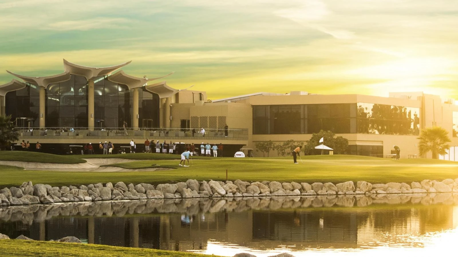 Golfers playing at Sharjah Golf and Shooting Club, scenic sunset view.