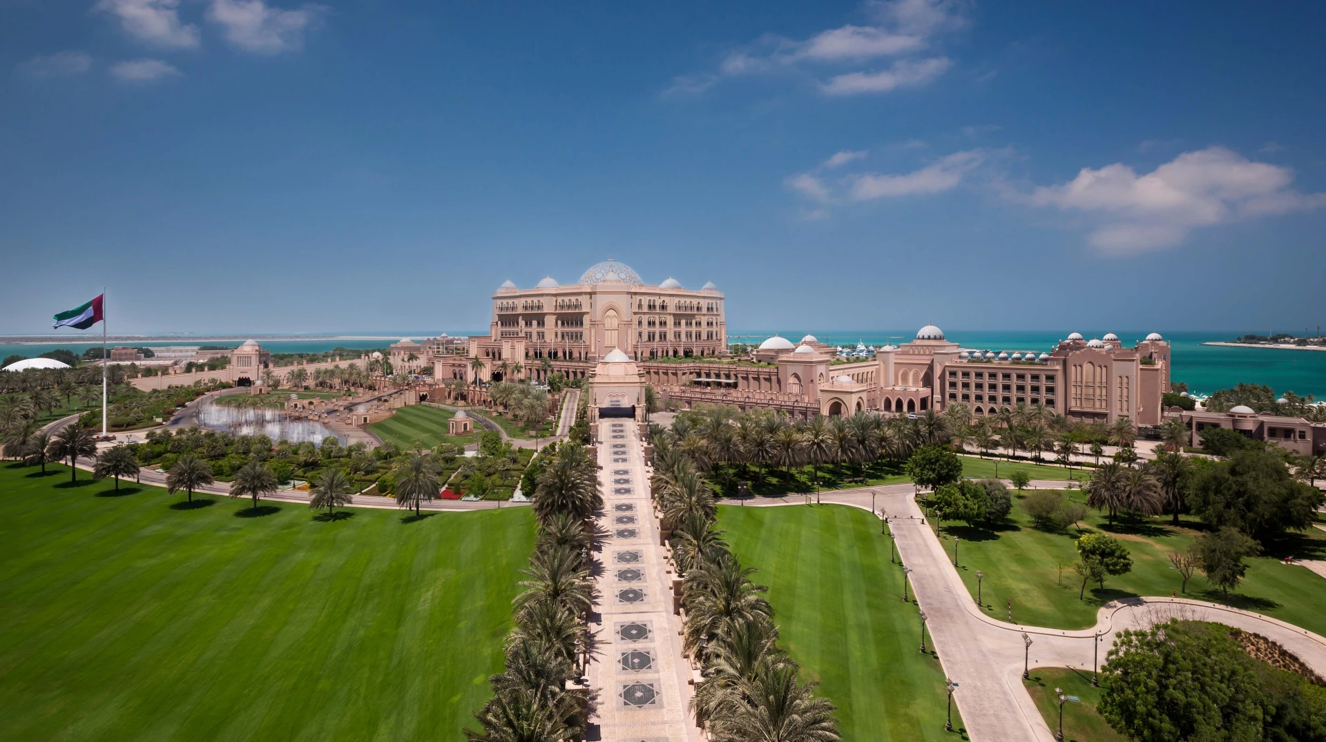 Emirates Palace Mandarin Oriental, Abu Dhabi, lush gardens, clear blue sky.