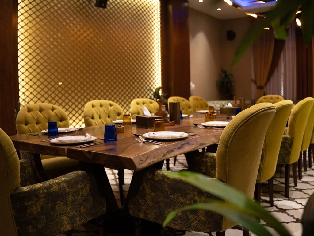Elegant dining setup at Al Meshwar Restaurant, Dubai with yellow chairs.