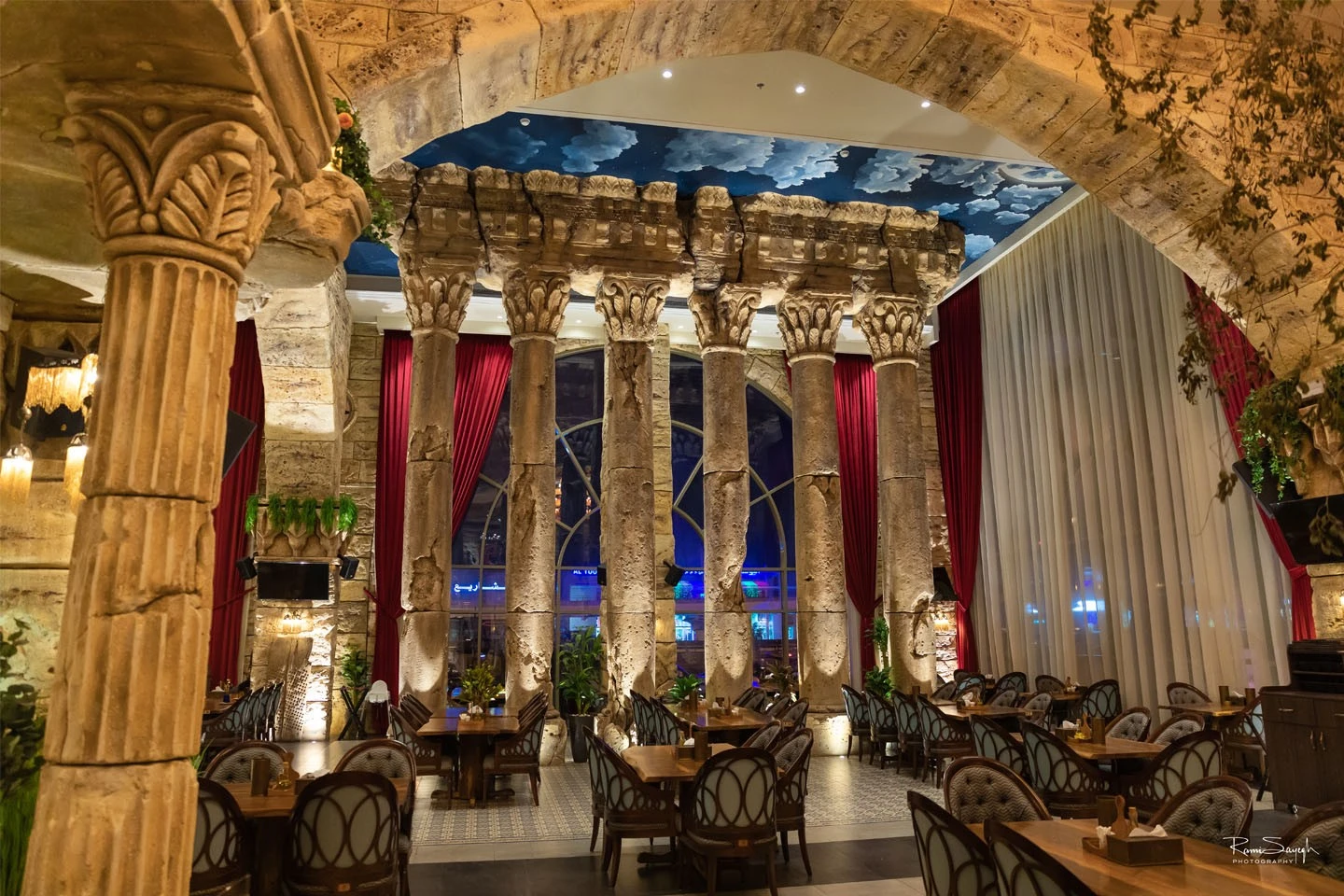 Al Meshwar Restaurant Dubai, elegant interior with stone columns and red curtains.