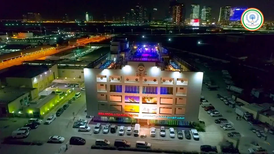 India Social & Cultural Centre illuminated at night, Dubai skyline visible.