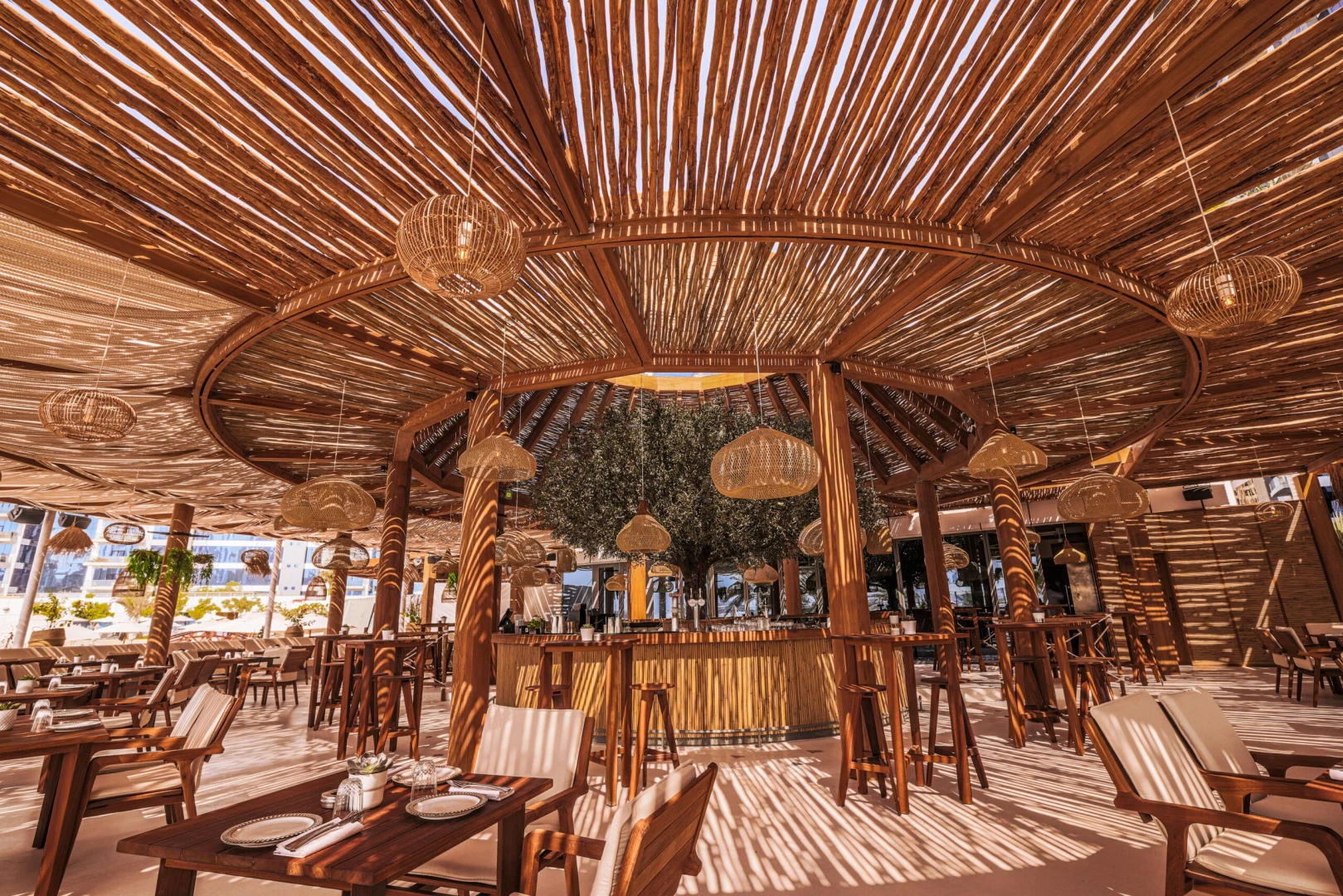 Ula Dubai Beach Club's stylish wooden interior with seating and bar.