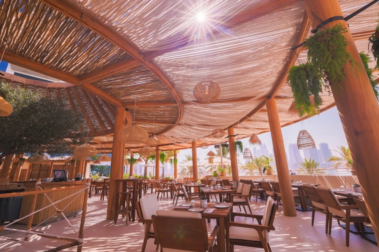 Ula Dubai Beach Club outdoor seating with wooden decor and city view.