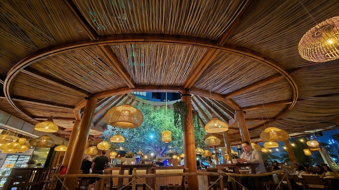 Ula Dubai Beach Club interior with bamboo ceiling and hanging lights.