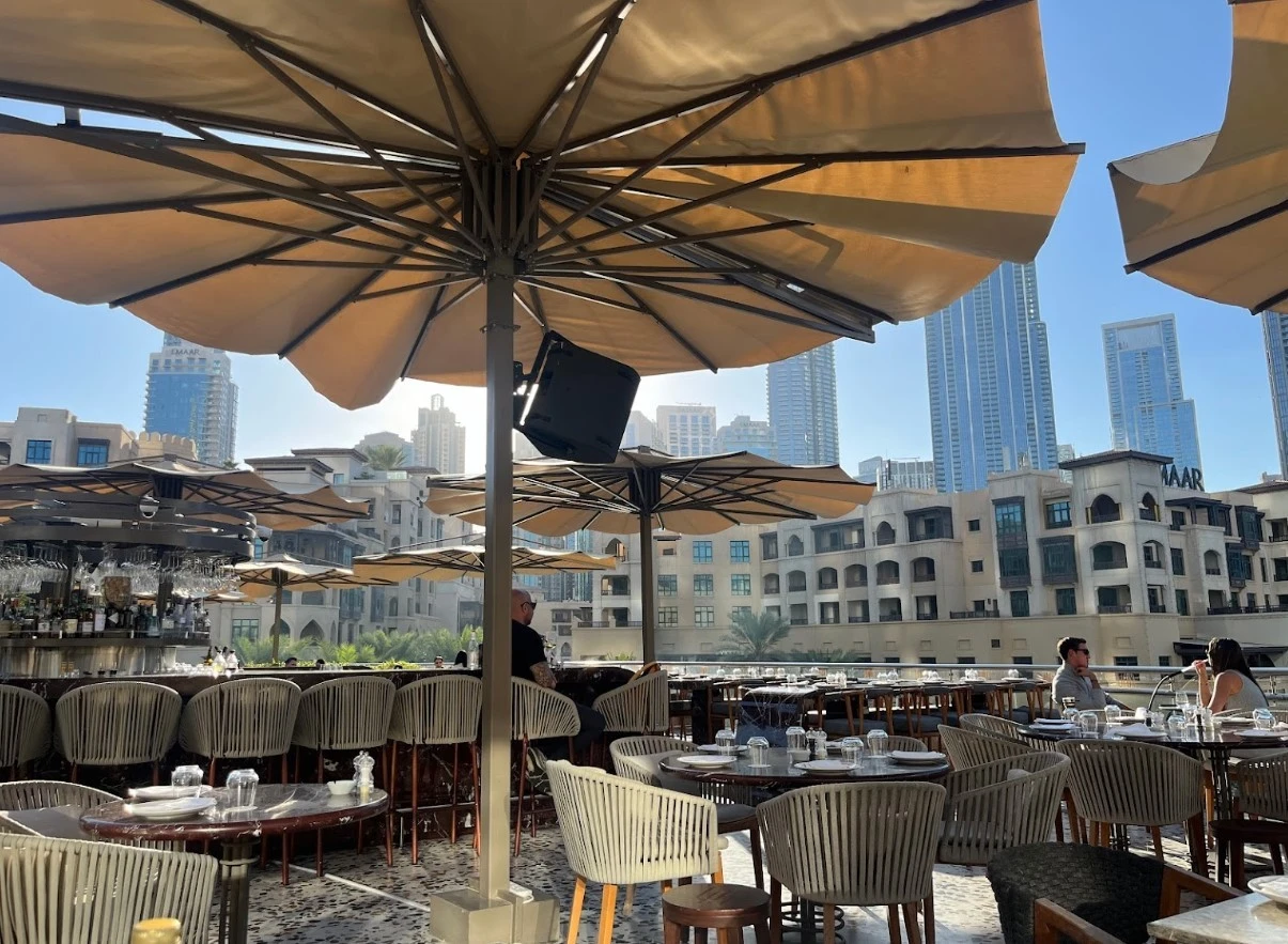 Outdoor seating at Ula Dubai Beach Club with city skyline view.