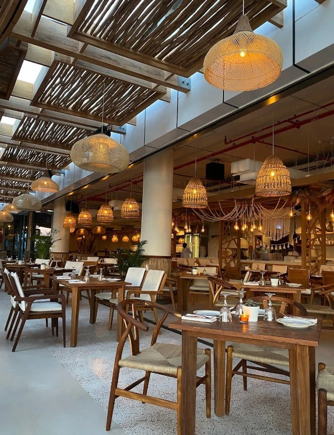 Ula Dubai Beach Club dining area with wooden tables and chairs.