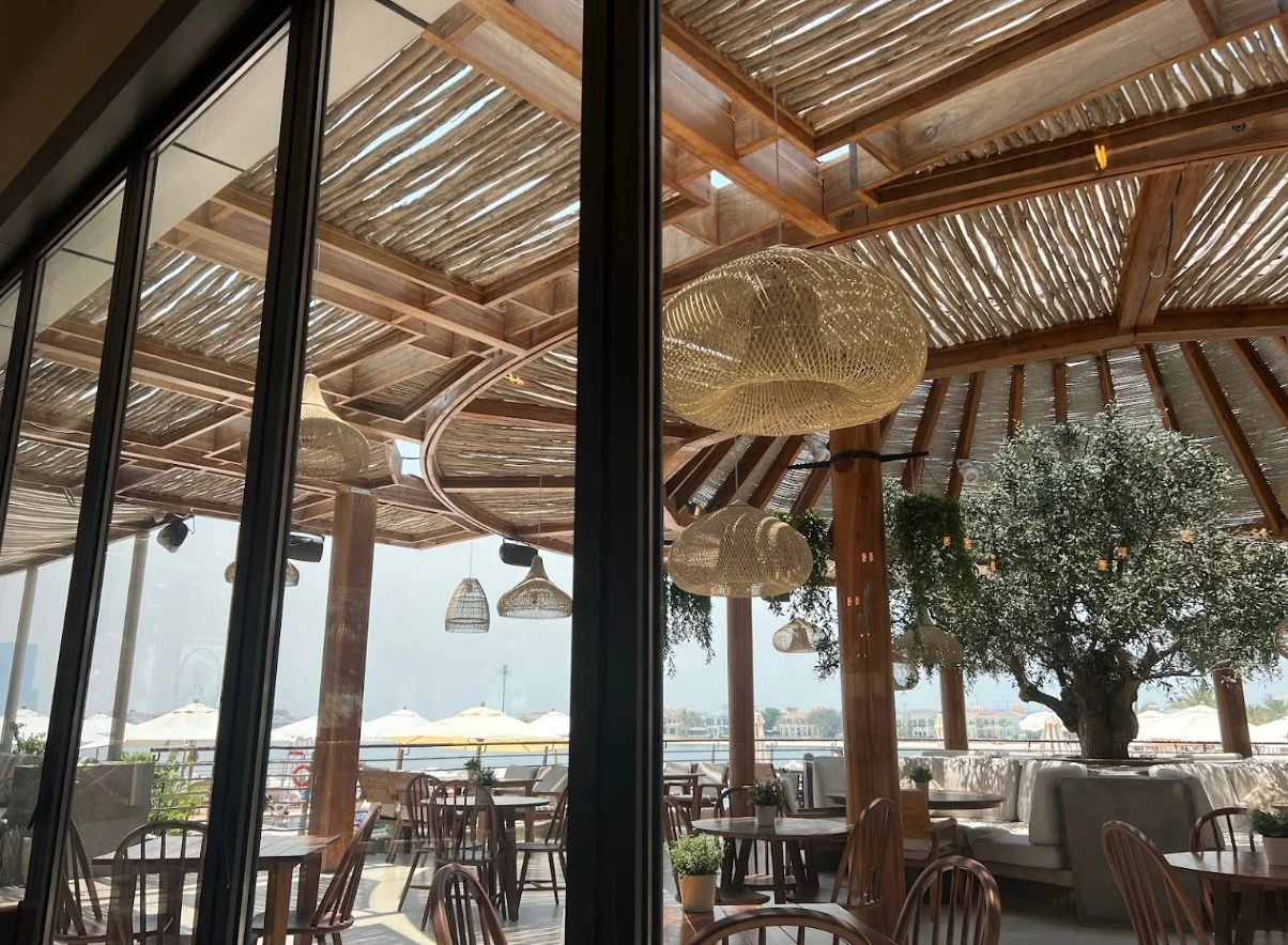 Ula Dubai Beach Club outdoor seating with wooden decor and sea view.
