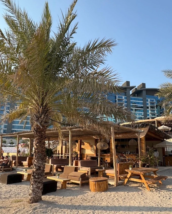Ula Dubai Beach Club with palm trees and outdoor seating.