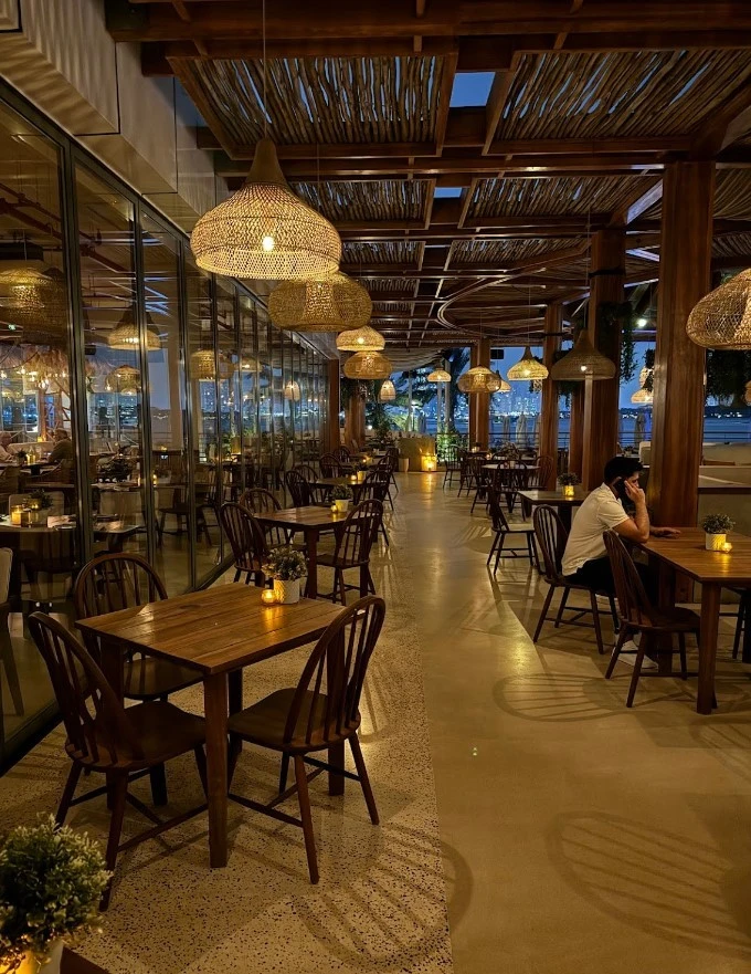 Ula Dubai Beach Club evening dining area with warm lighting.