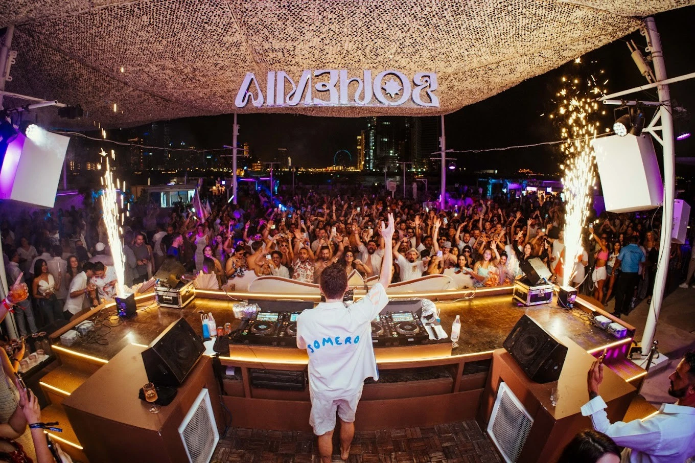 DJ performing at Bohemia Beach Club Dubai, lively night crowd.