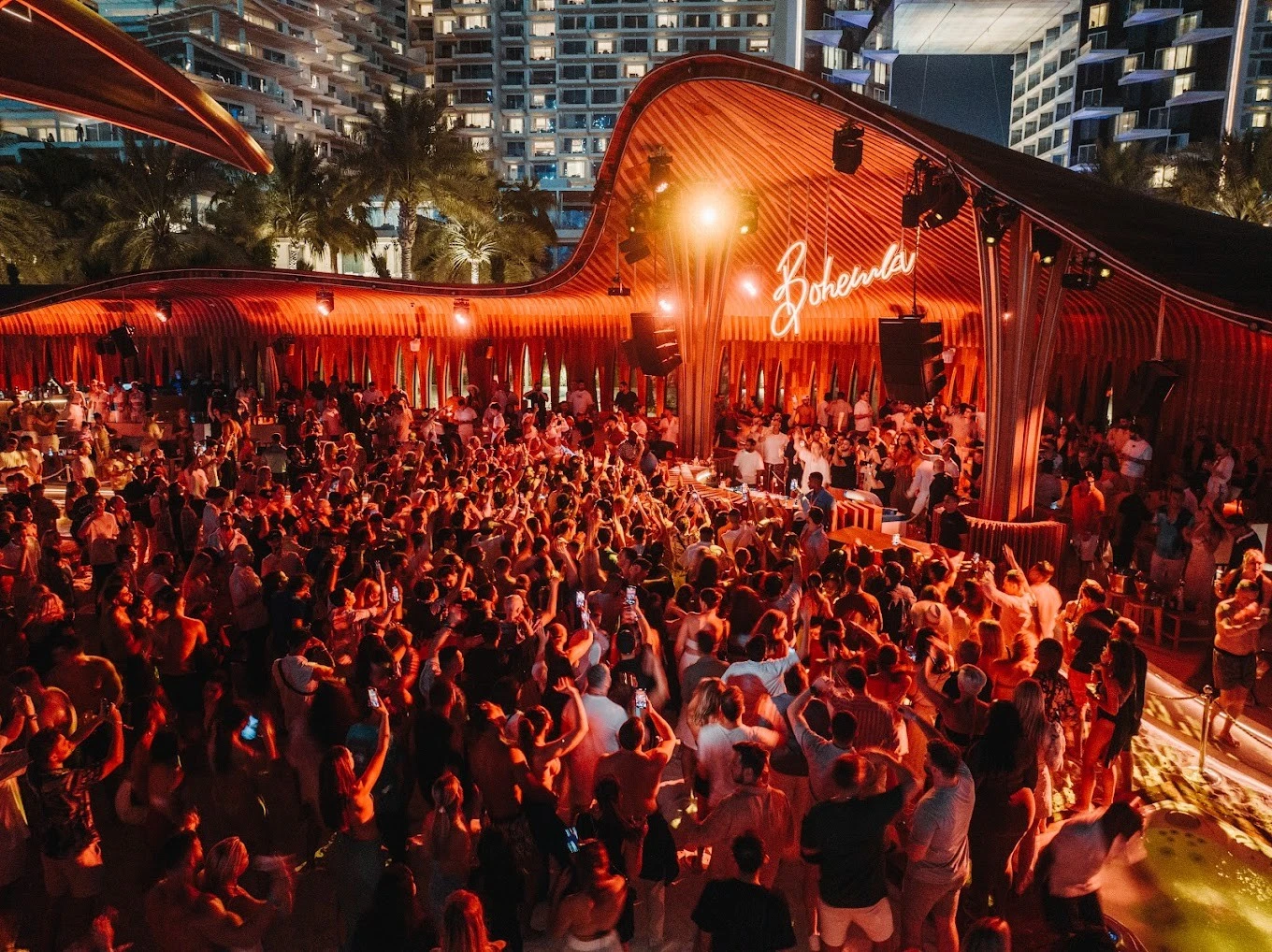 Crowded party at Bohemia Beach Club Dubai, vibrant evening atmosphere.