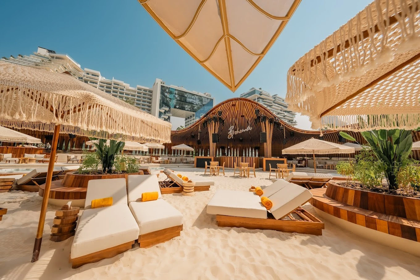 Bohemia Beach Club Dubai with sun loungers and parasols on sandy beach.