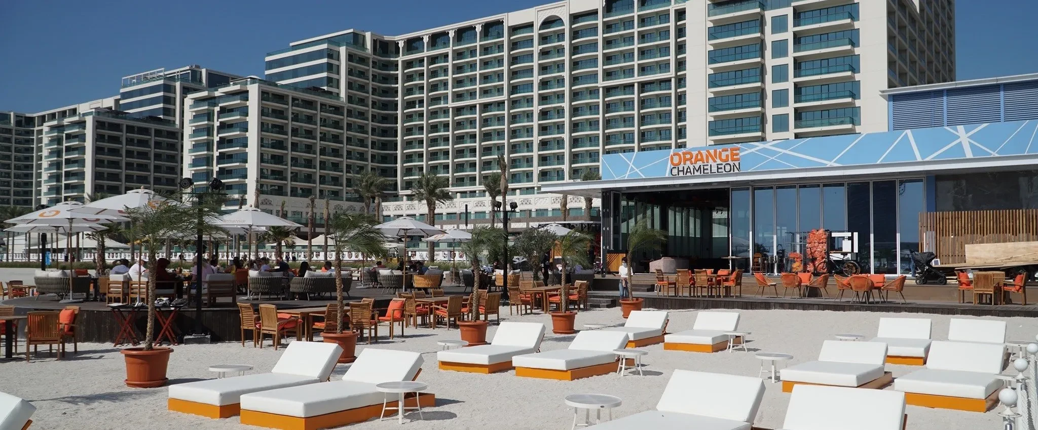 Beachfront lounge seating at Orange Chameleon, Dubai, daytime view.