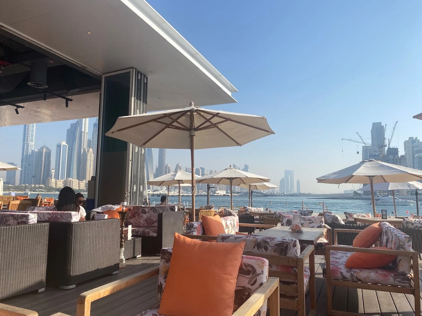 Outdoor seating at Orange Chameleon Restaurant & Lounge, Dubai waterfront view.