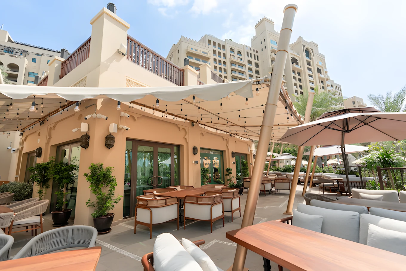 Outdoor seating at Grand Zor Restaurant Dubai with umbrellas and plants.