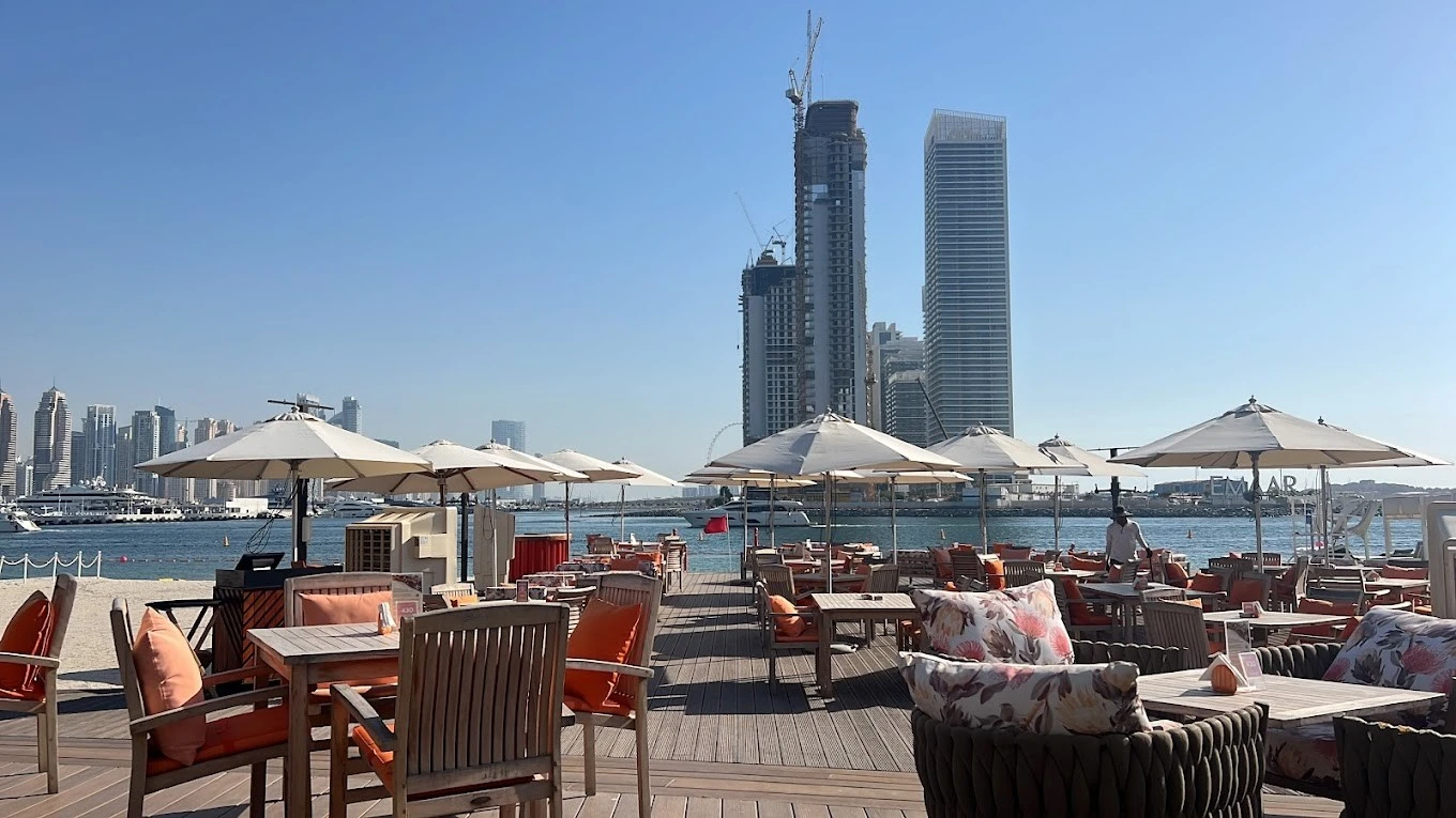 Terrace seating at Orange Chameleon, Dubai skyline and waterfront backdrop.