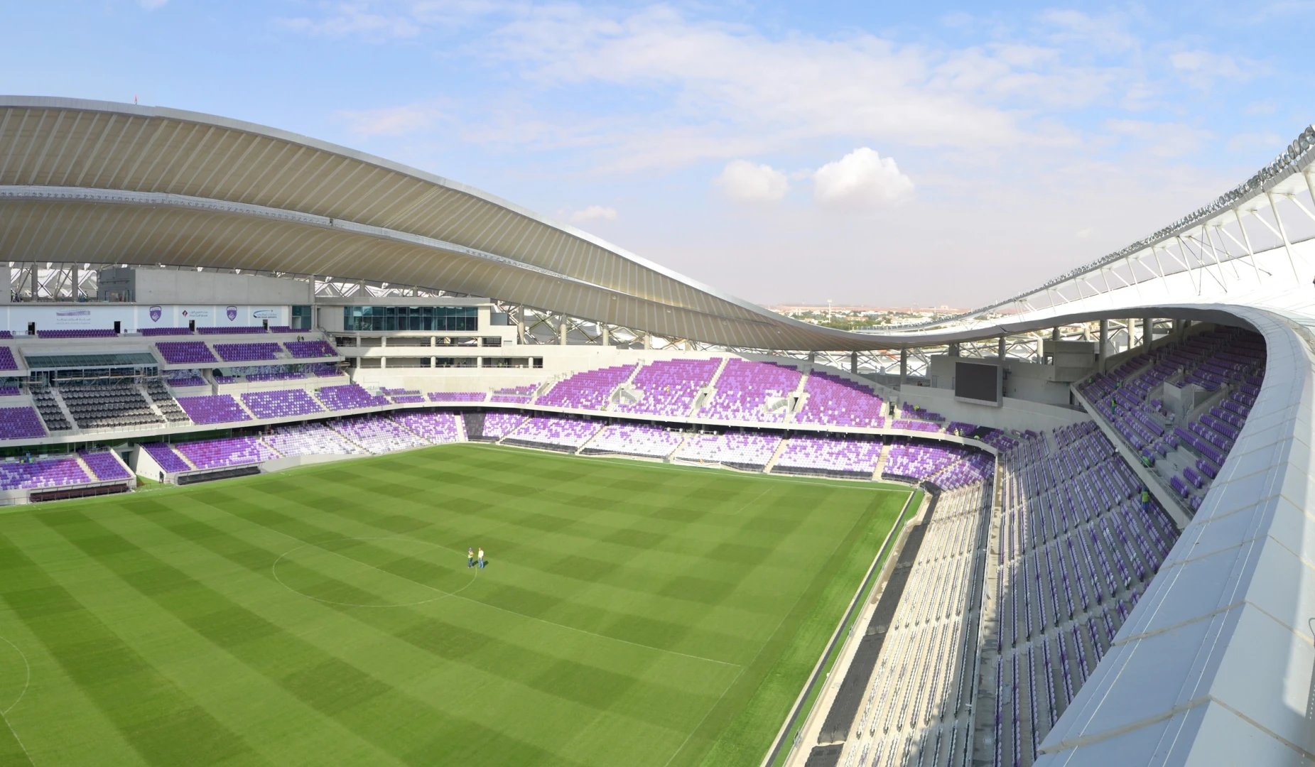 Hazza Bin Zayed Stadium in Al Ain, empty with green field.