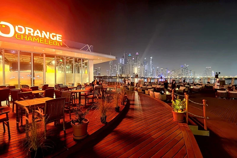 Orange Chameleon Restaurant Dubai, outdoor seating with city skyline view.
