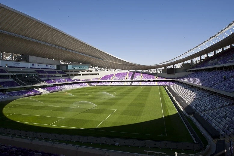 Sprinklers watering green field at Hazza Bin Zayed Stadium, Al Ain.