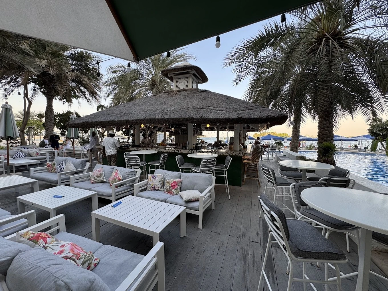 Outdoor seating at The Byron Bathers Beach Club, Dubai, with palm trees.