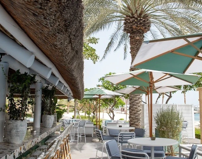 Shaded outdoor seating with greenery at Byron Bathers Beach Club, Dubai.