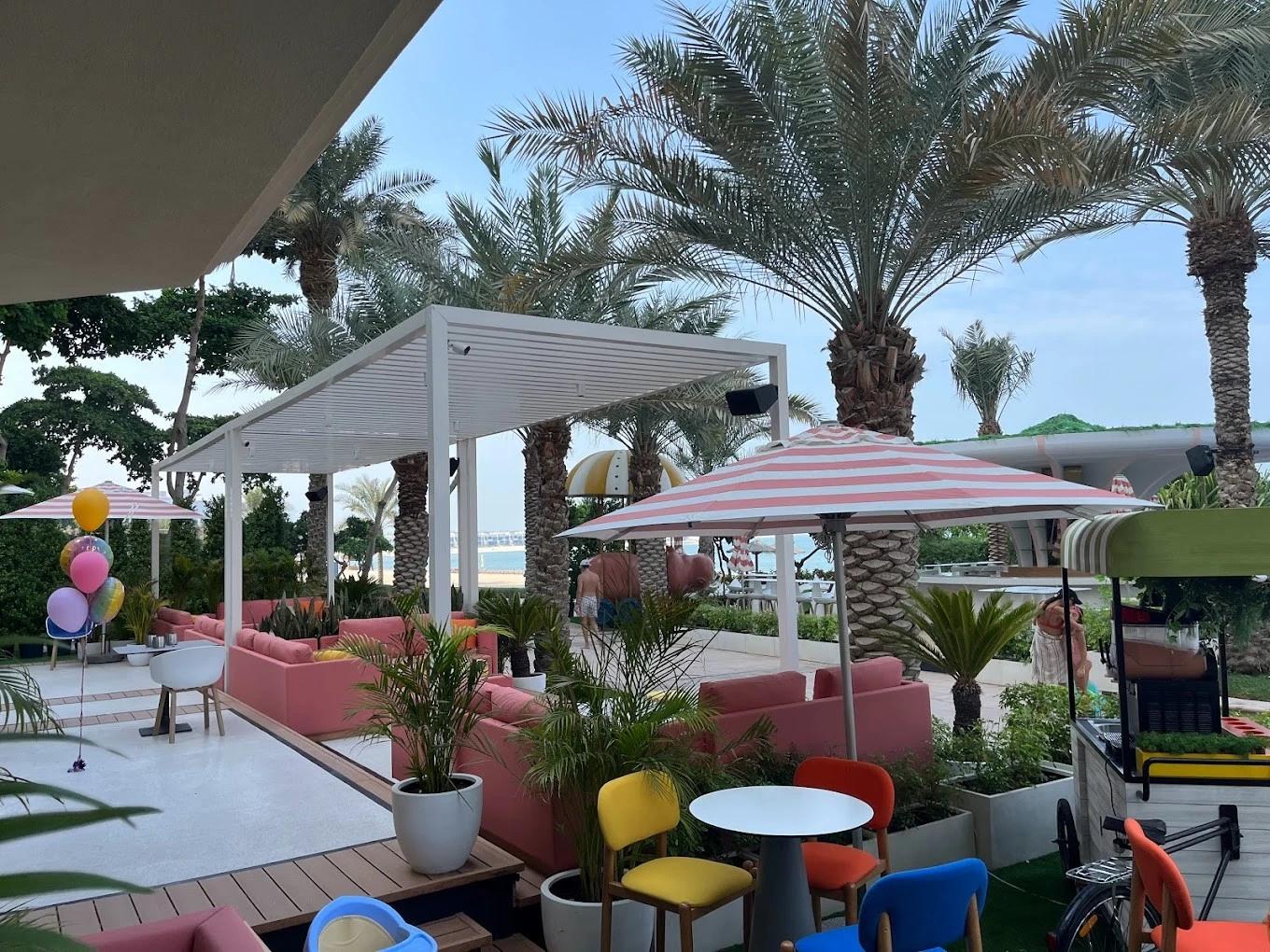 Outdoor seating at Peaches & Cream Beach Restaurant, Dubai with palm trees.