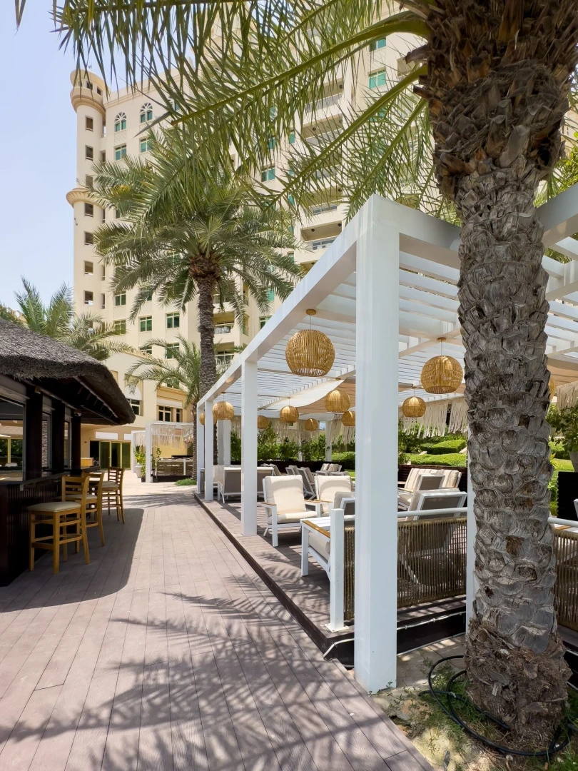Outdoor seating with palm trees at Cabana On The Beach, Dubai.