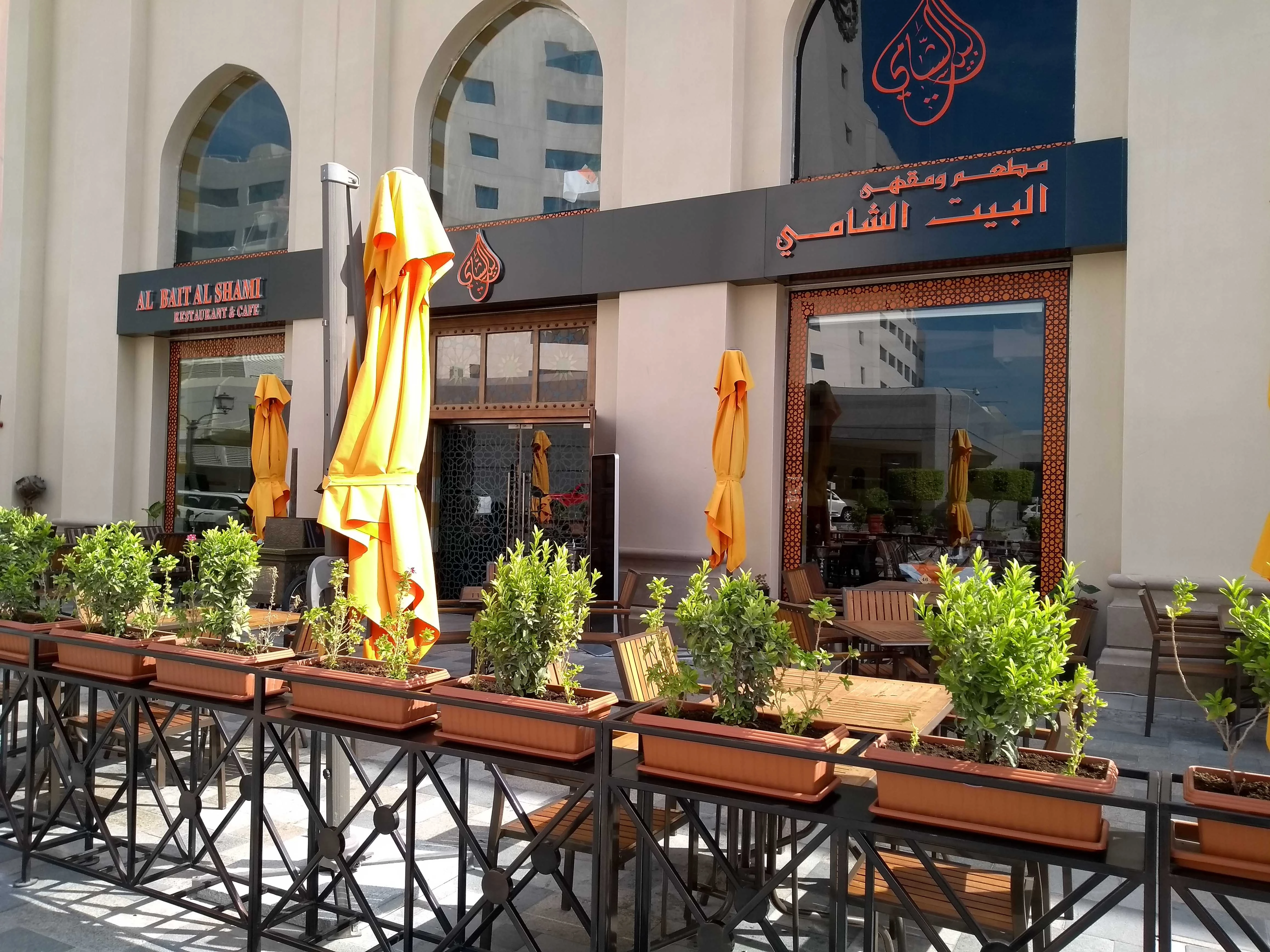 Al Bait Al Shami Restaurant outdoor seating, Dubai, with orange umbrellas.