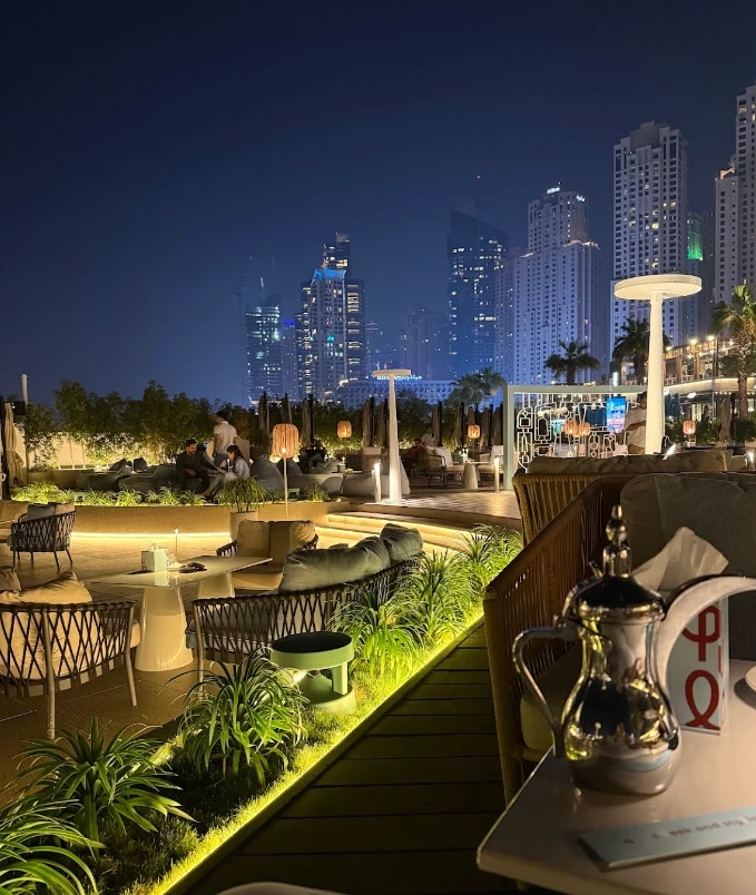 Yula Lounge rooftop with Dubai skyline at night, cozy seating area.