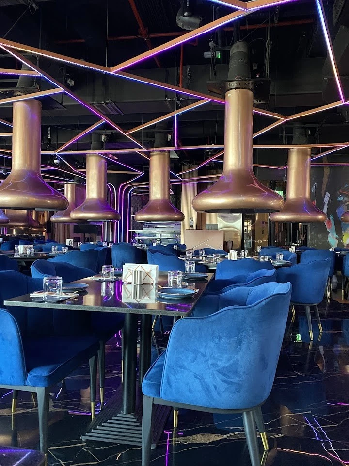 KUKU Restaurant Dubai, elegant interior with blue chairs and modern lighting.