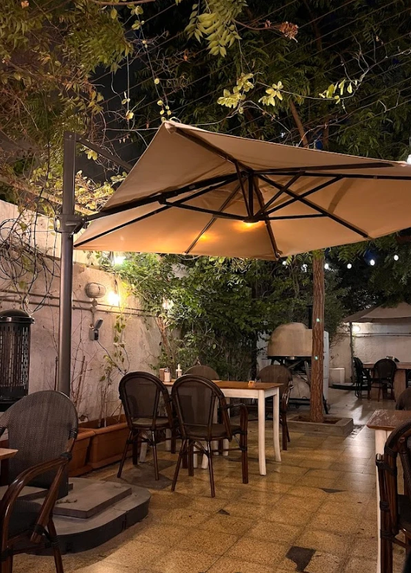 Outdoor seating at Mamaesh Al Manara, Dubai, under large umbrella.