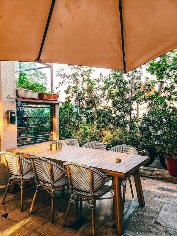 Outdoor seating at Mamaesh Al Manara, Dubai, with wooden table and chairs.