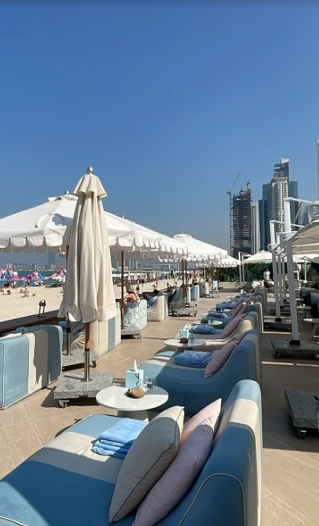 Yula Lounge beachfront seating with umbrellas, Dubai skyline in background.