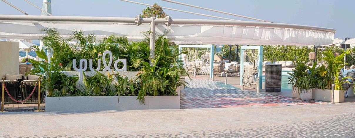 Entrance to Yula Lounge, Dubai with greenery and seating area.