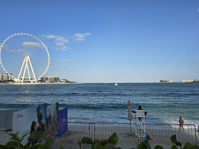 Dubai Marina beach view with Ferris wheel and lifeguard chair.