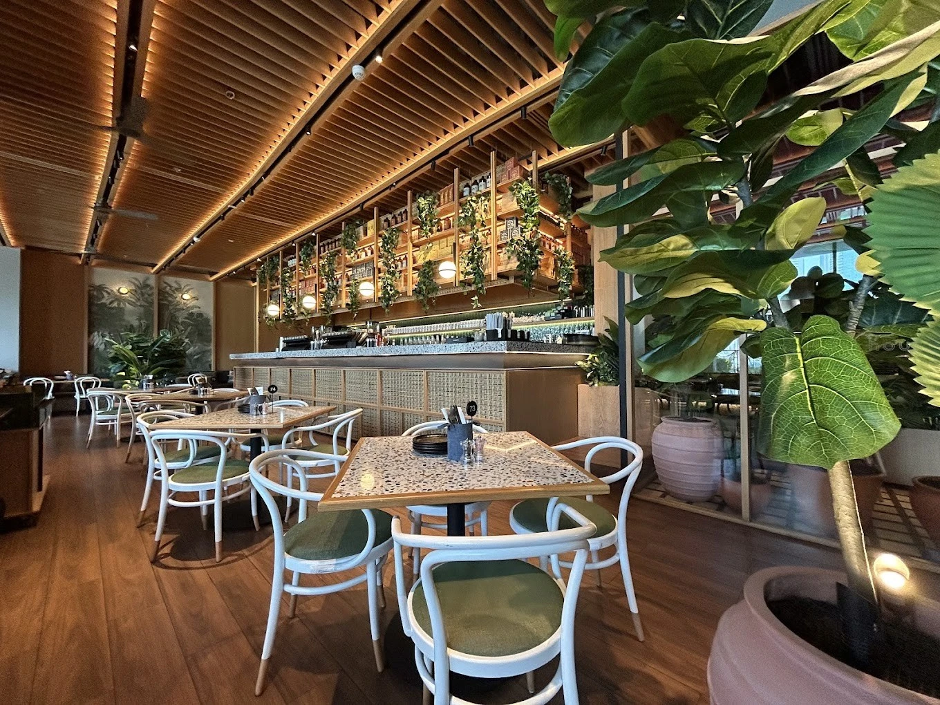 Social House Restaurant Dubai interior with wooden decor and green plants.