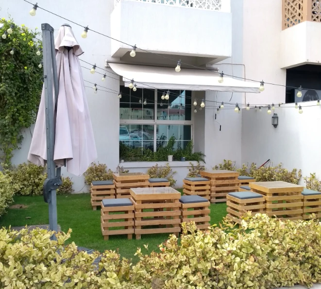 Wooden patio seating at Fiks Coffee Umm Suqeim, Dubai with lights.