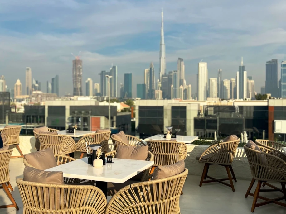 Lune Lounge rooftop with Dubai skyline view, wicker chairs and tables.